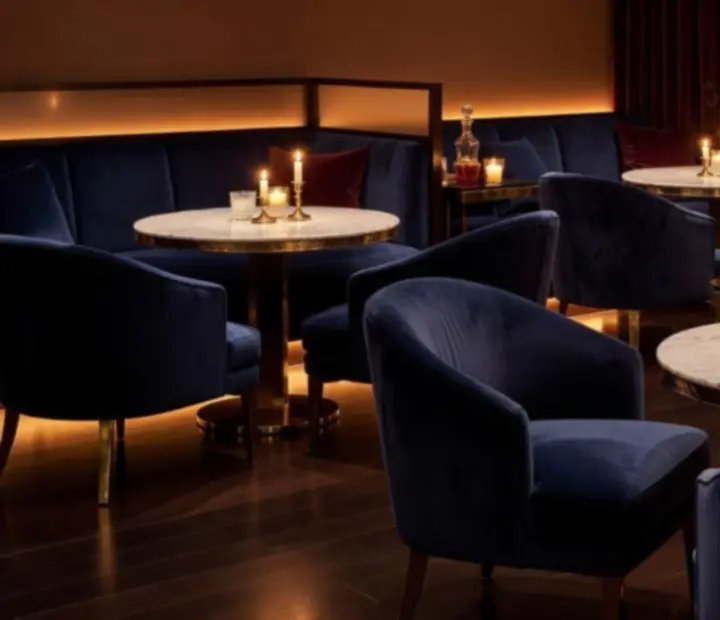 Meleg fényekkel megvilágított VIP lounge márvány asztalokkal és bársony fotelekkel